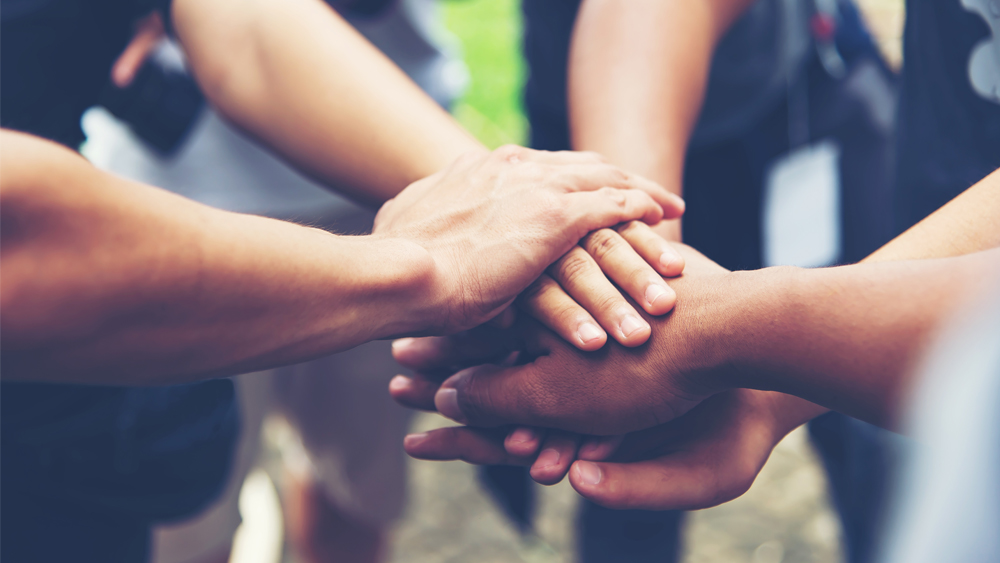 The picture shows the hands of people of different colours.