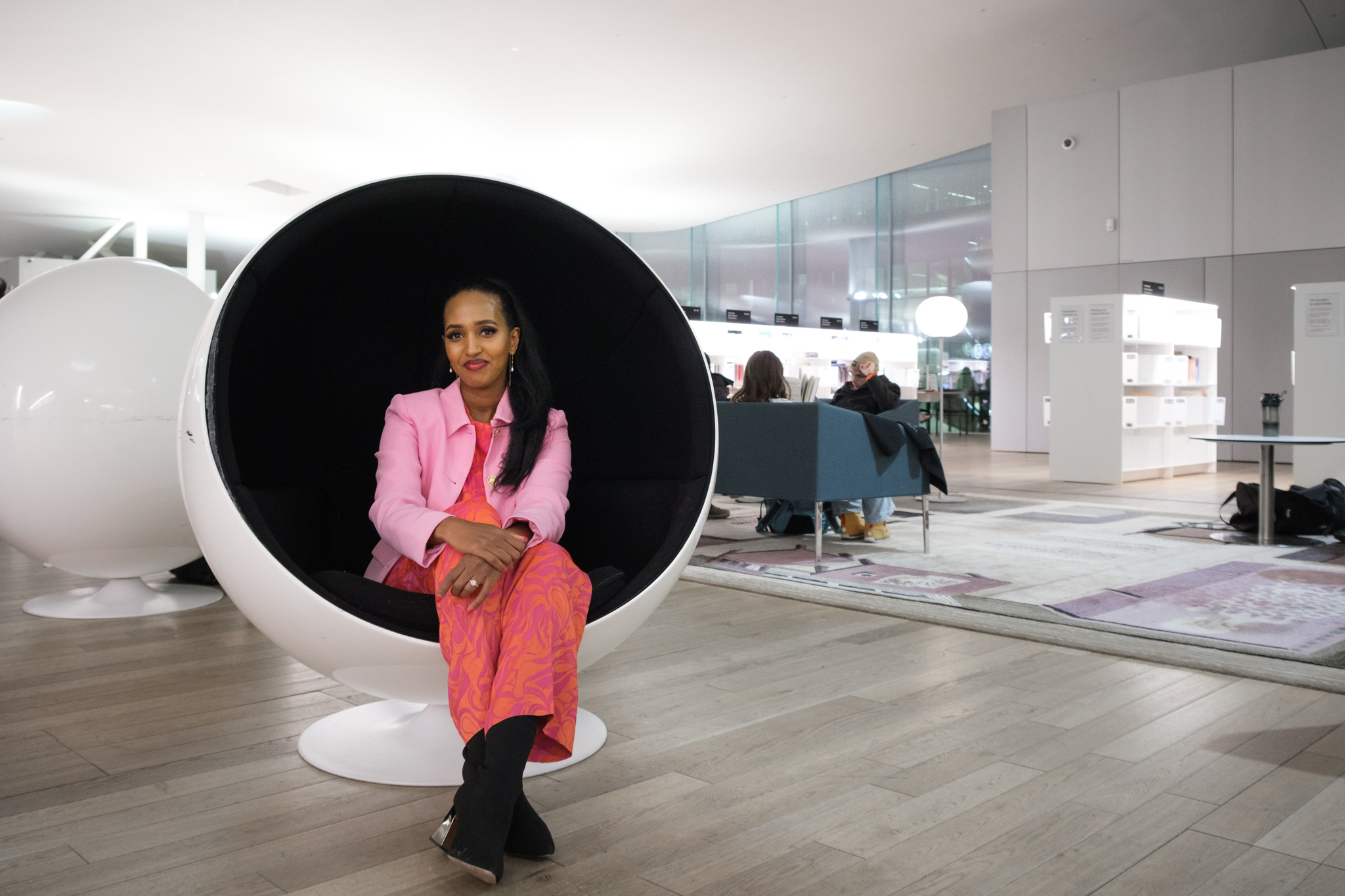 Ujuni Ahmed sitting in a round chair smiling.